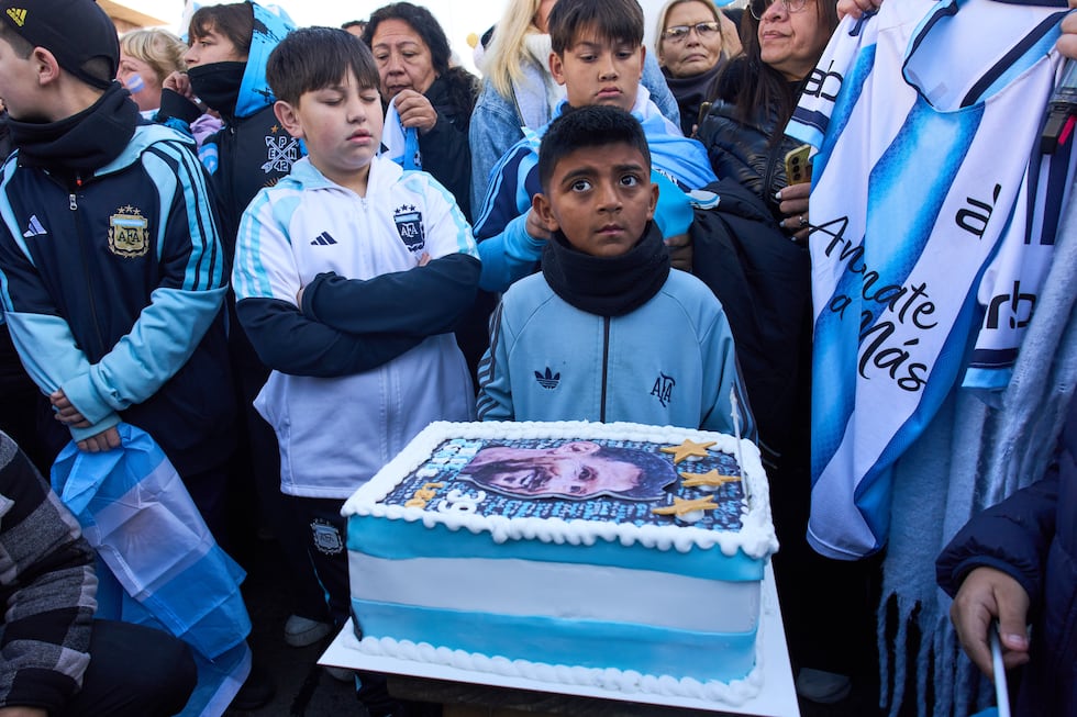 Boys stand next to a cake that reads in Spanish: "Happy Birthday", during a celebration to...