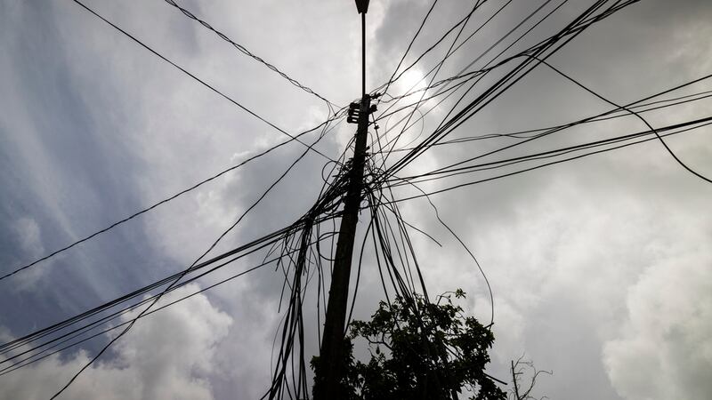 FILE - A utility pole with loose cables towers over a home in Loiza, Puerto Rico, Sept. 15, 2022.