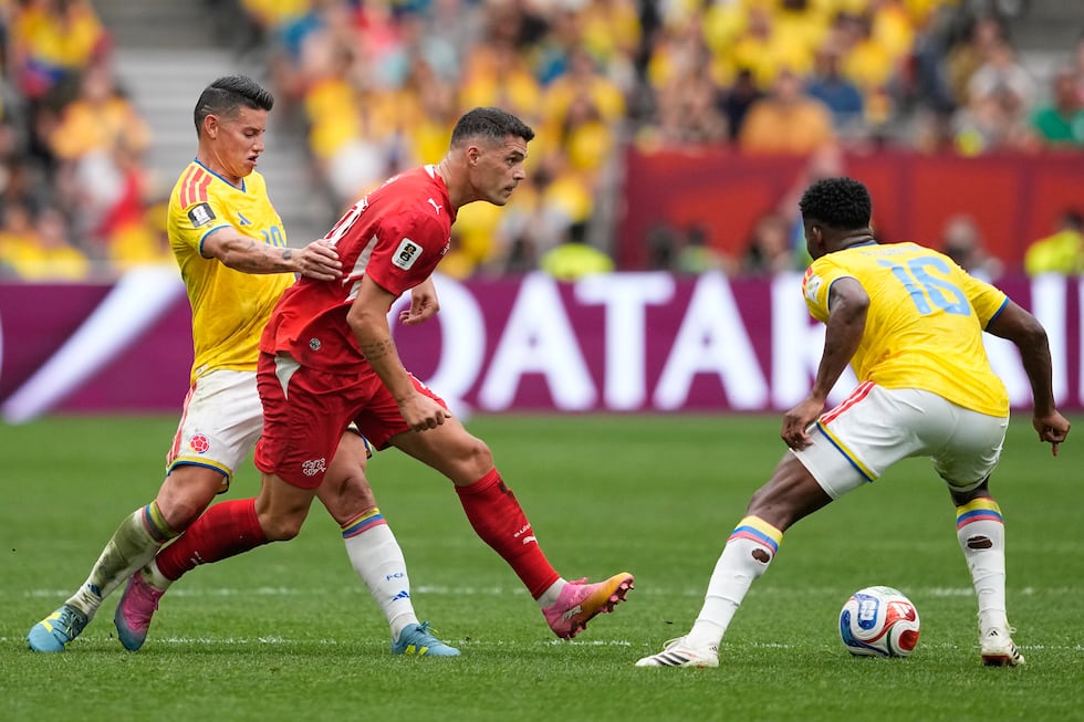 Switzerland's Granit Xhaka, center, tries to get past Colombia's James Rodríguez, left, and...